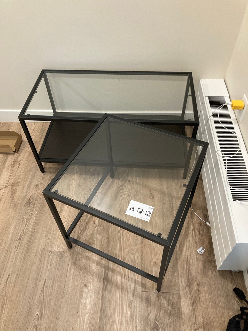 Two black-frame glass tables assembled in a Regina home
